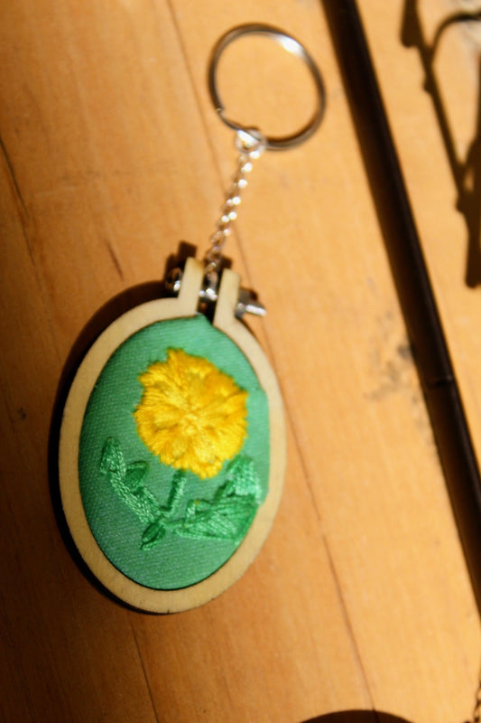 Keychain with yellow flower design on a wooden surface