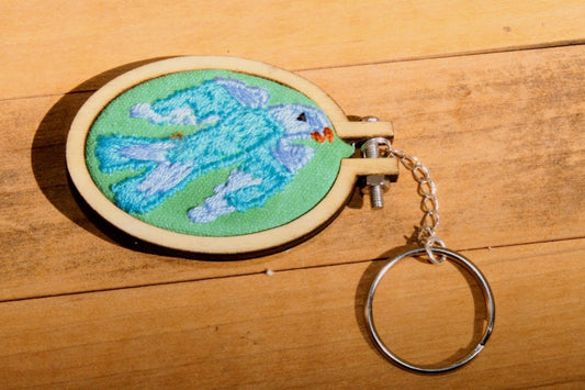 Embroidered keychain with a blue and green design on a wooden surface